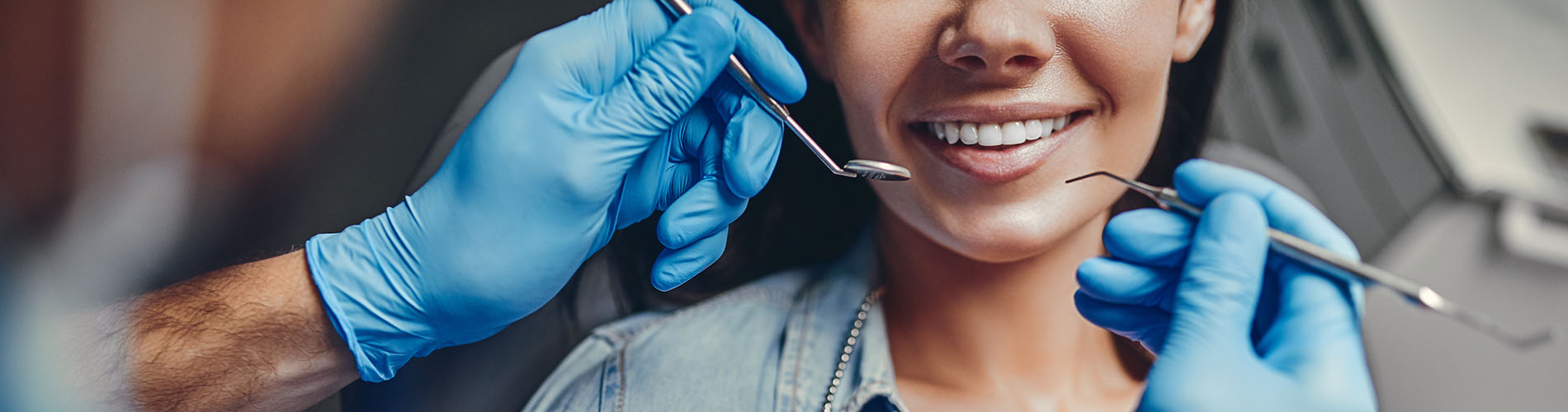 The image shows a person receiving dental care with a dentist s hands visible, holding tools near the patient s mouth.
